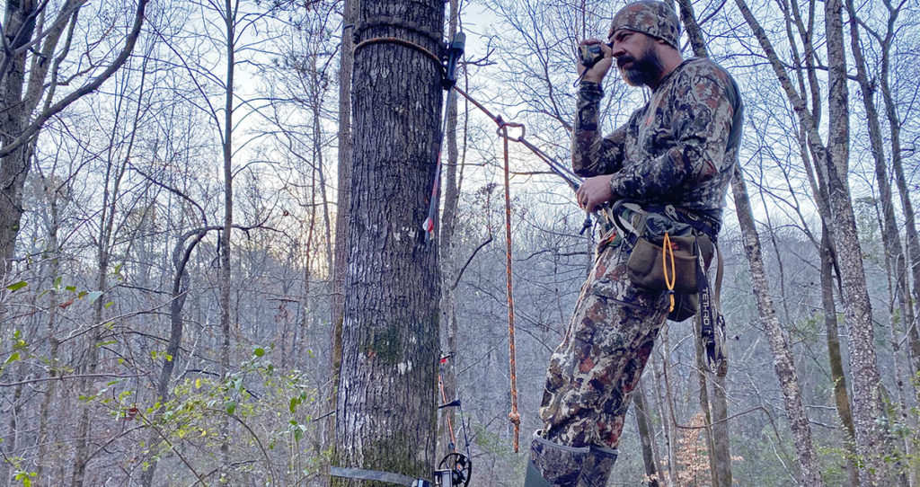 The author looking through a rangefinder while hanging in his hunting saddle.