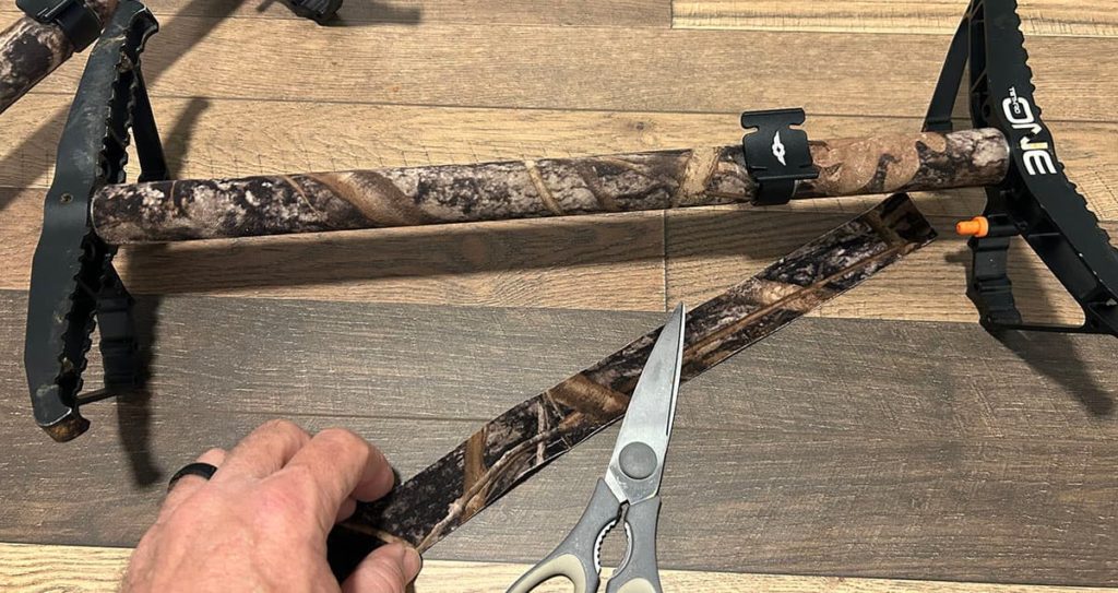 Stealth strip camouflage tape being put on a climbing stick to help keep in as quiet as possible.