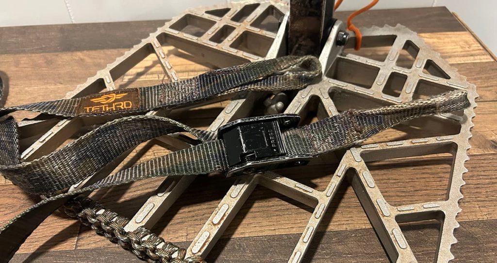 The large metal buckle of a Tethrd platform strap sitting on the Predator XL.