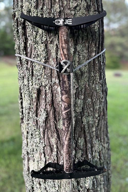 Camouflaged Tethrd One stick mounted to a tree.